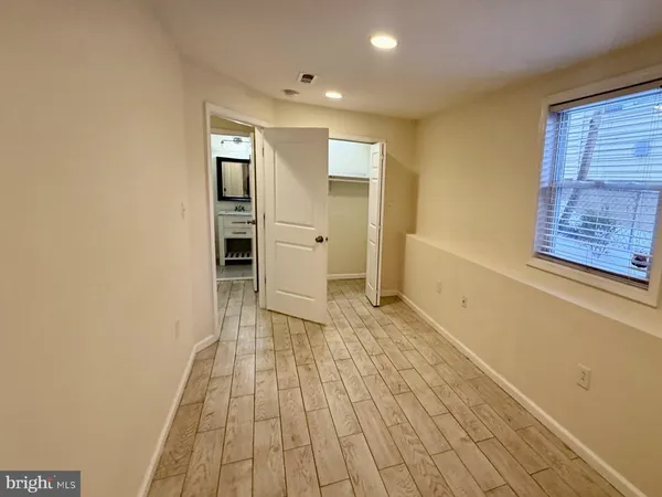 a view of a hallway with wooden floor and closet