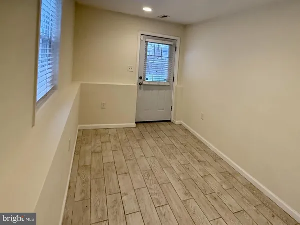 an empty room with wooden floor and windows