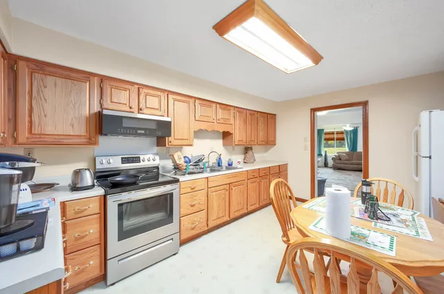 a kitchen with stainless steel appliances granite countertop a stove top oven a sink dishwasher and white cabinets with wooden floor