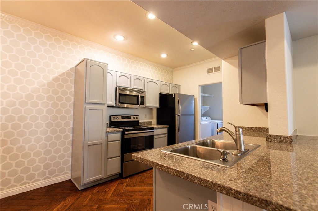 a kitchen with stainless steel appliances granite countertop a sink refrigerator and microwave