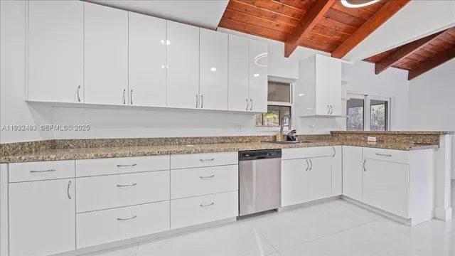 a kitchen with granite countertop white cabinets and stainless steel appliances