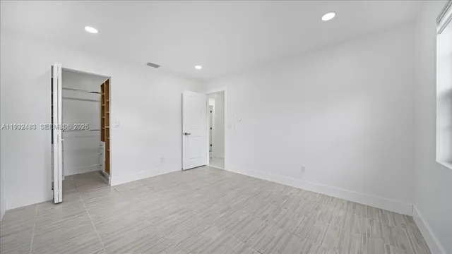 a view of an empty room with wooden floor and closet