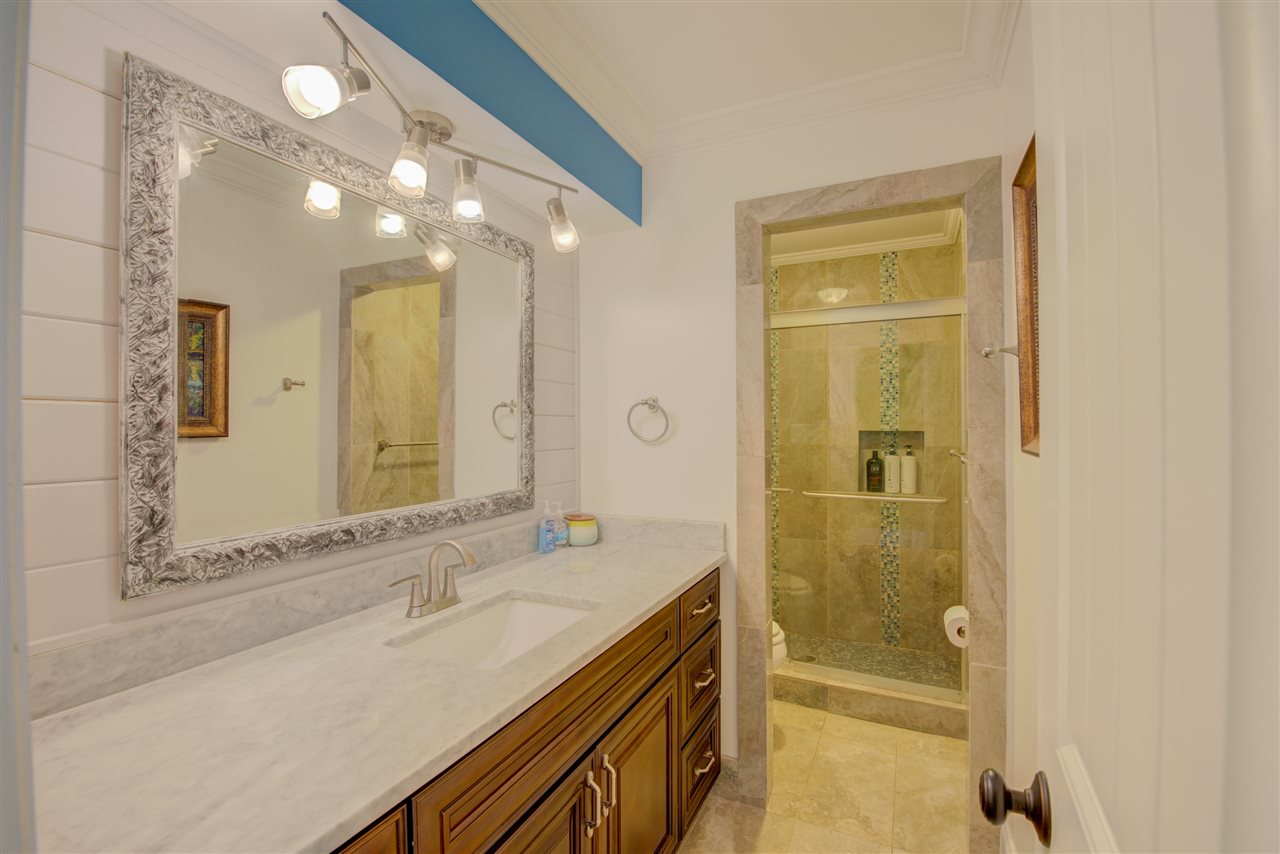 1915 Corbin Road Germantown, TN 38139 - Photo 18 of 25 Remodeled shared full hall bathroom with tile flooring, European style track lighting, marble vanity with beautiful cabinetry, and a walk-in shower with a complete tile surround.