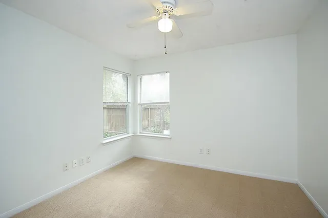 an empty room with a window and a fan