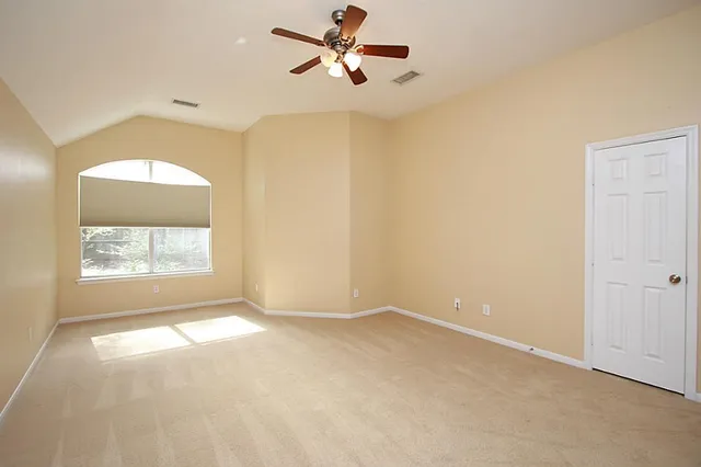 an empty room with windows and fan