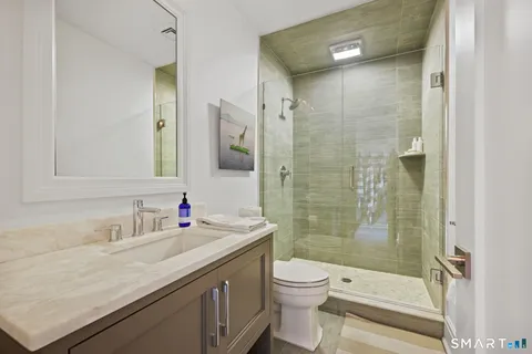 a bathroom with a granite countertop sink a toilet and shower