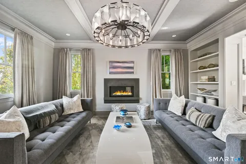 a living room with couches a coffee table and kitchen view with wooden floor