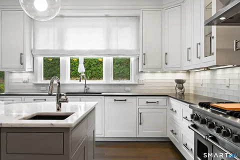 a dining room with wooden floor a chandelier a wooden table and chairs