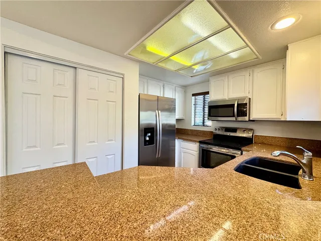 a kitchen with stainless steel appliances kitchen island granite countertop a refrigerator stove and sink