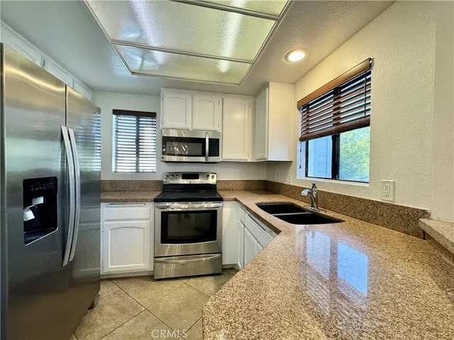 a kitchen with granite countertop a sink stainless steel appliances and cabinets