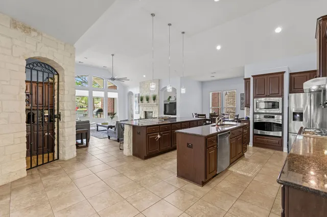 a large kitchen with stainless steel appliances kitchen island granite countertop wooden cabinets a sink dishwasher a stove and a refrigerator