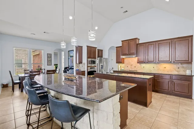 a kitchen with stainless steel appliances granite countertop table chairs sink refrigerator and cabinets