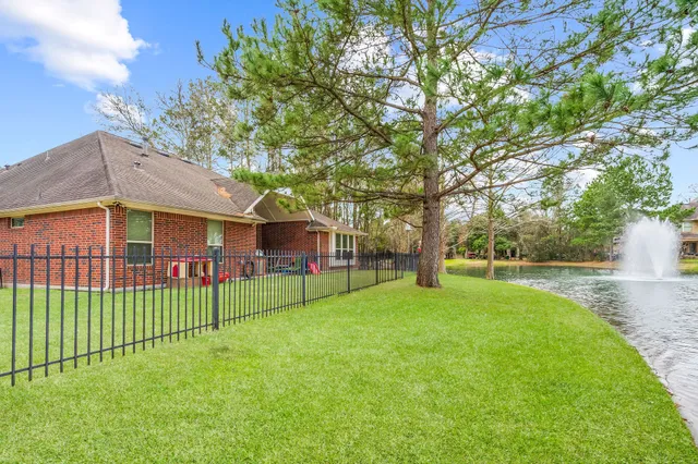 a view of a house with a yard and a large tree