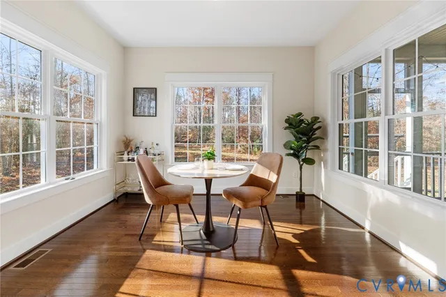 a dining room with wooden floor a glass table and windows