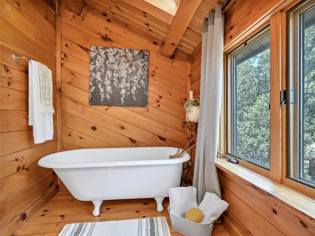18304 West Reed Park Road Jonestown, TX 78645 - Photo 19 of 24 Rich wood paneling, vaulted ceilings, and a classic clawfoot tub create a cozy cabin retreat.