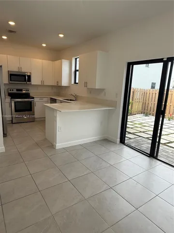 a kitchen with granite countertop a stove a sink and a refrigerator