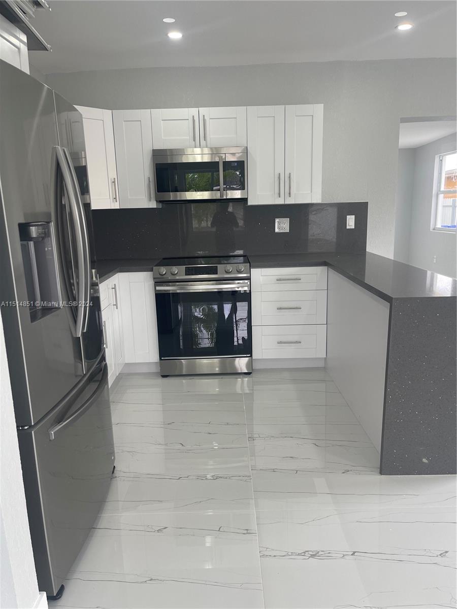 516 Southwest 66th Avenue Miami, FL 33144 - Photo 6 of 27 a kitchen with stainless steel appliances granite countertop a refrigerator a stove a sink and a microwave