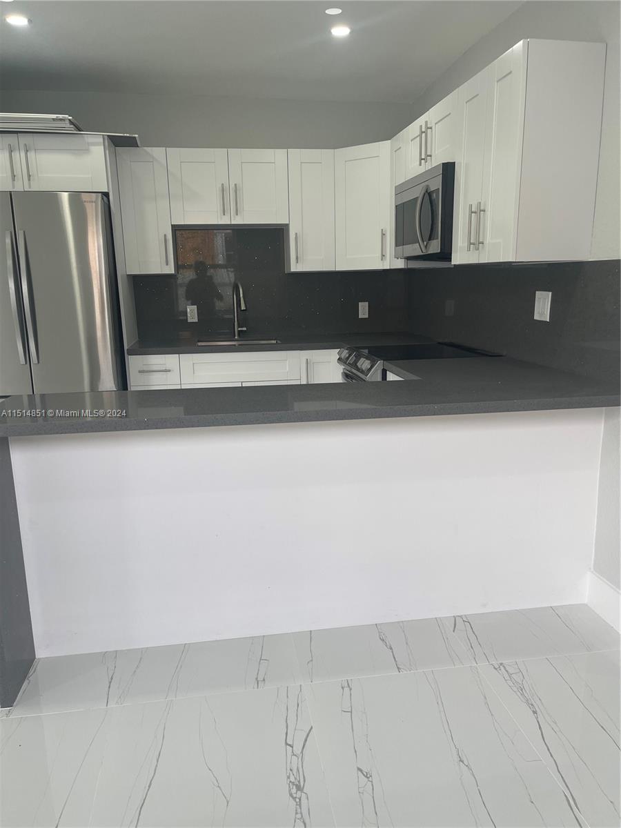 516 Southwest 66th Avenue Miami, FL 33144 - Photo 7 of 27 a kitchen with stainless steel appliances a refrigerator sink and cabinets