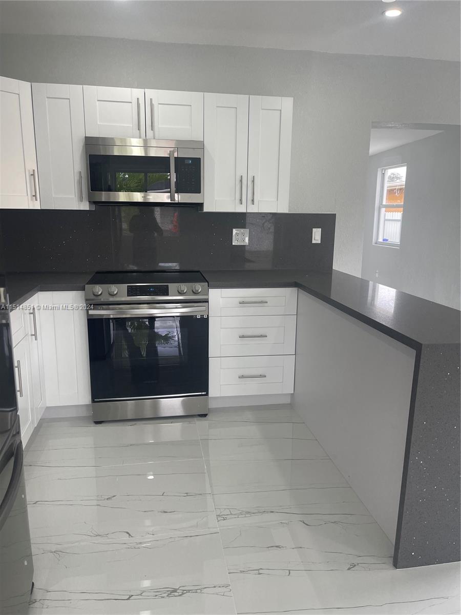 516 Southwest 66th Avenue Miami, FL 33144 - Photo 9 of 27 a kitchen with a stove and white cabinets