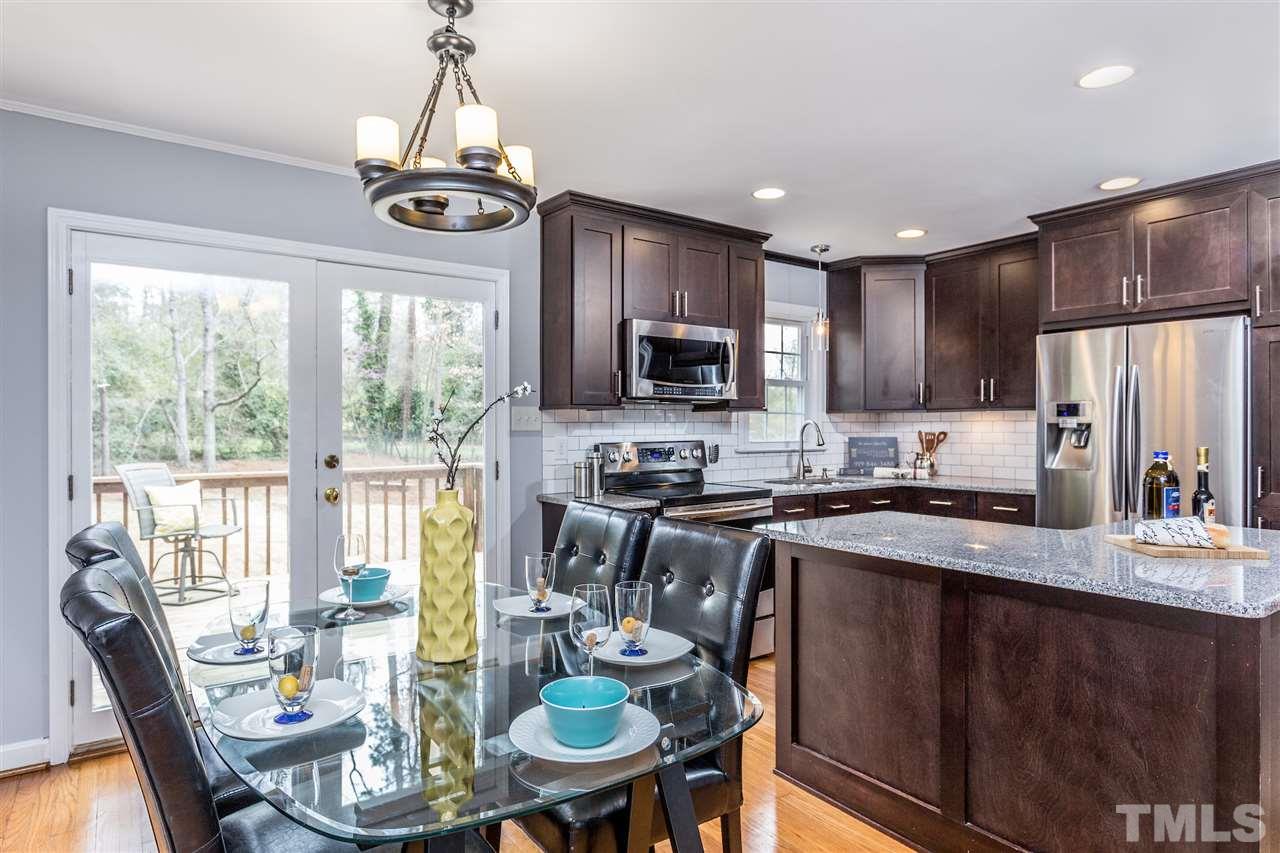 2612 Barmettler Street Raleigh, NC 27607 - Photo 6 of 24 a kitchen with stainless steel appliances granite countertop a stove top oven a sink dishwasher a dining table and chairs with wooden floor