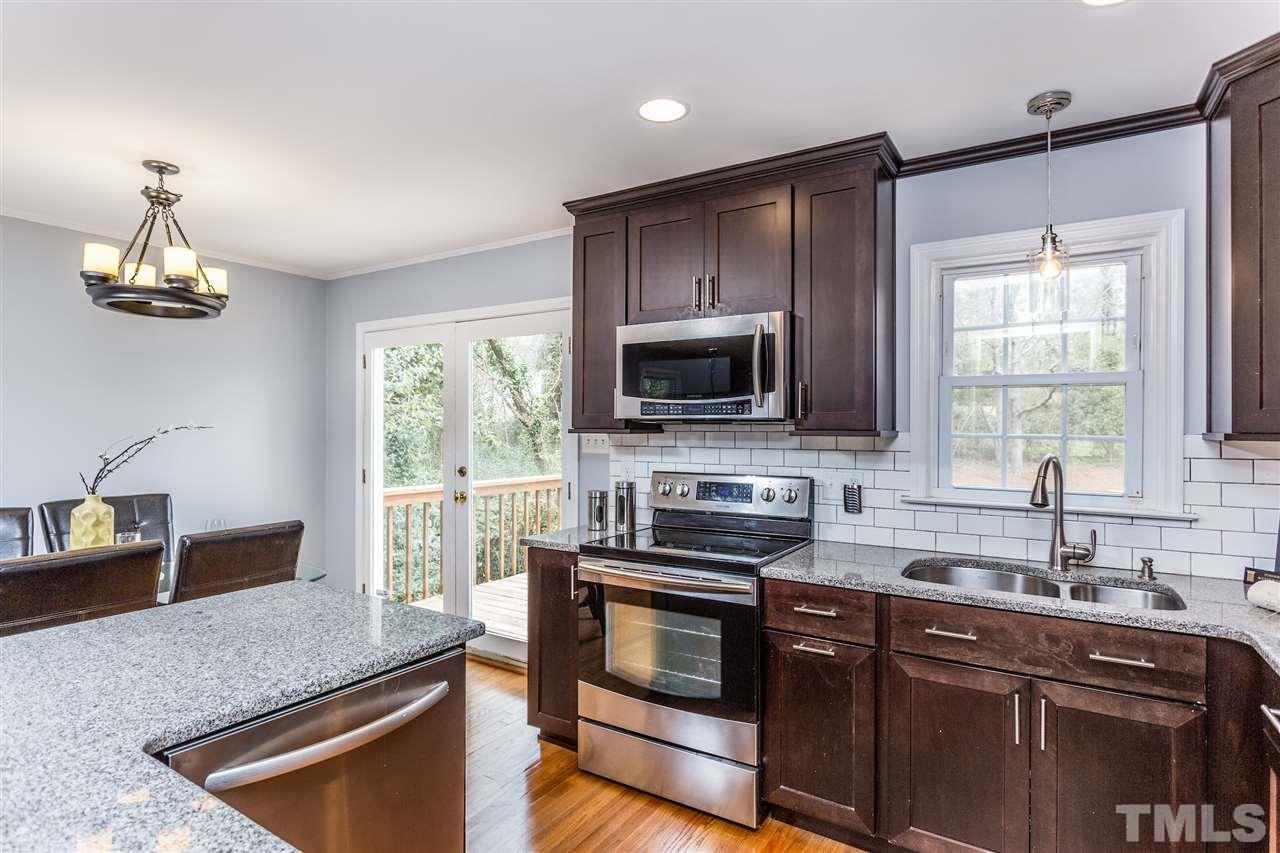 2612 Barmettler Street Raleigh, NC 27607 - Photo 8 of 24 a kitchen with kitchen island granite countertop a sink cabinets and window