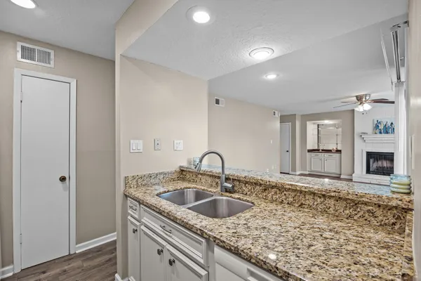 a kitchen with granite countertop a sink a stove and cabinets