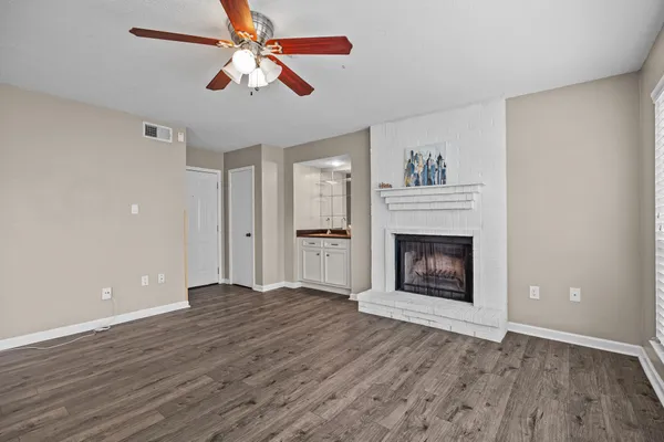a view of an empty room with wooden floor fireplace and a window