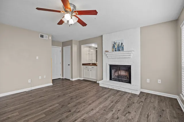 a view of an empty room with wooden floor fireplace and a window