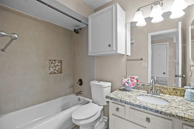 a bathroom with a granite countertop sink mirror vanity and toilet