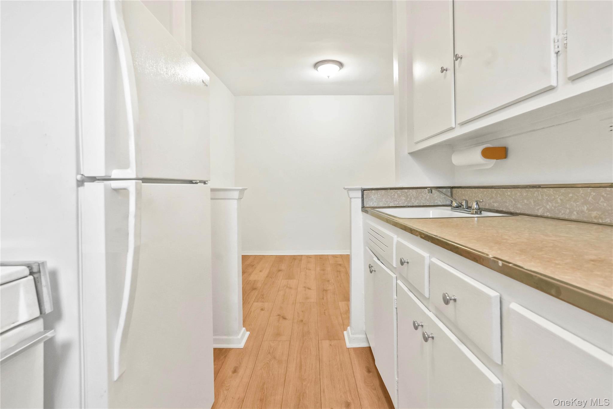 110-15 71st Road, Unit 6J Queens, NY 11375 - Photo 15 of 23 a view of a kitchen with white cabinets and wooden floor