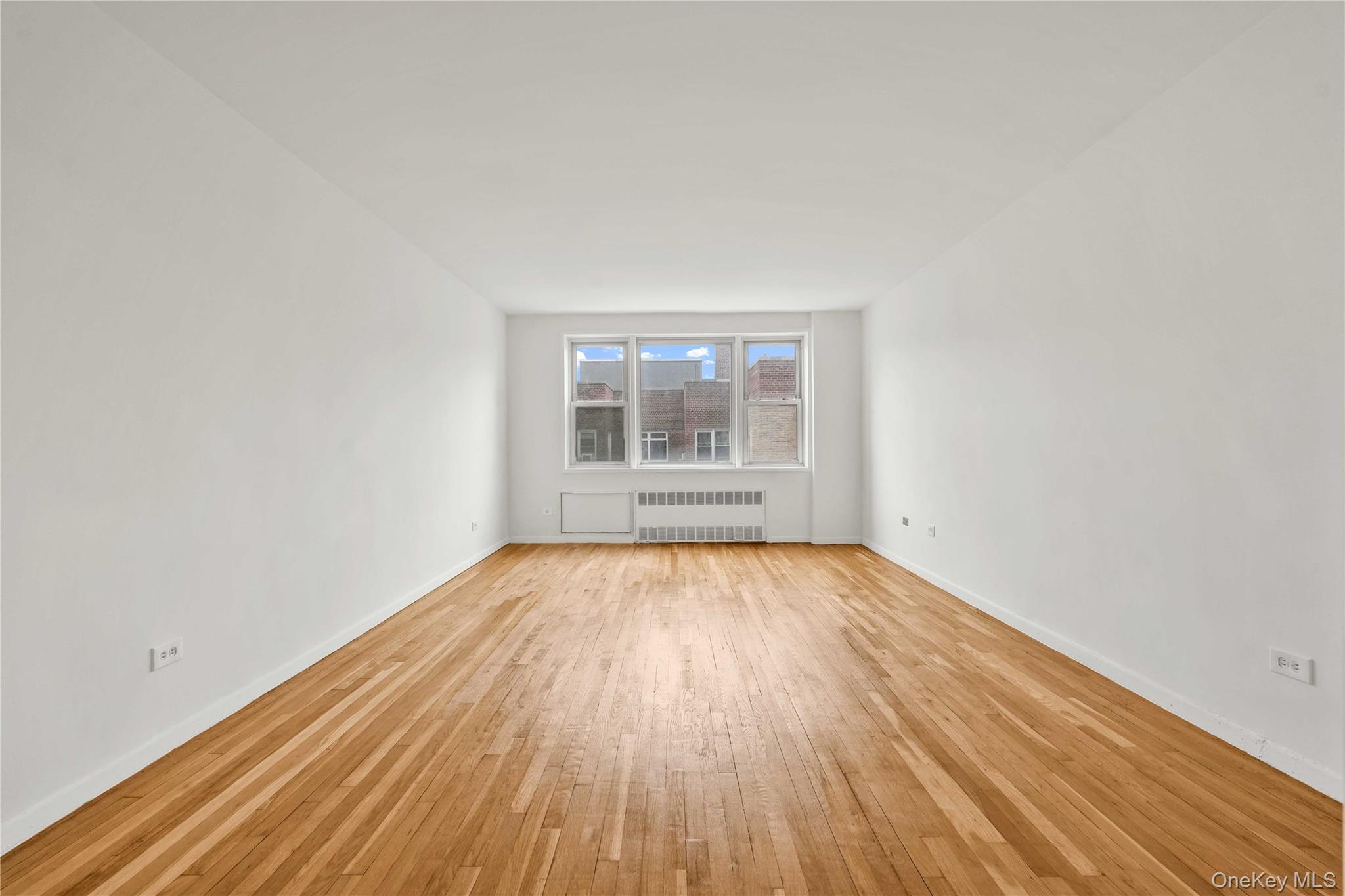 110-15 71st Road, Unit 6J Queens, NY 11375 - Photo 3 of 23 an empty room with wooden floor and windows