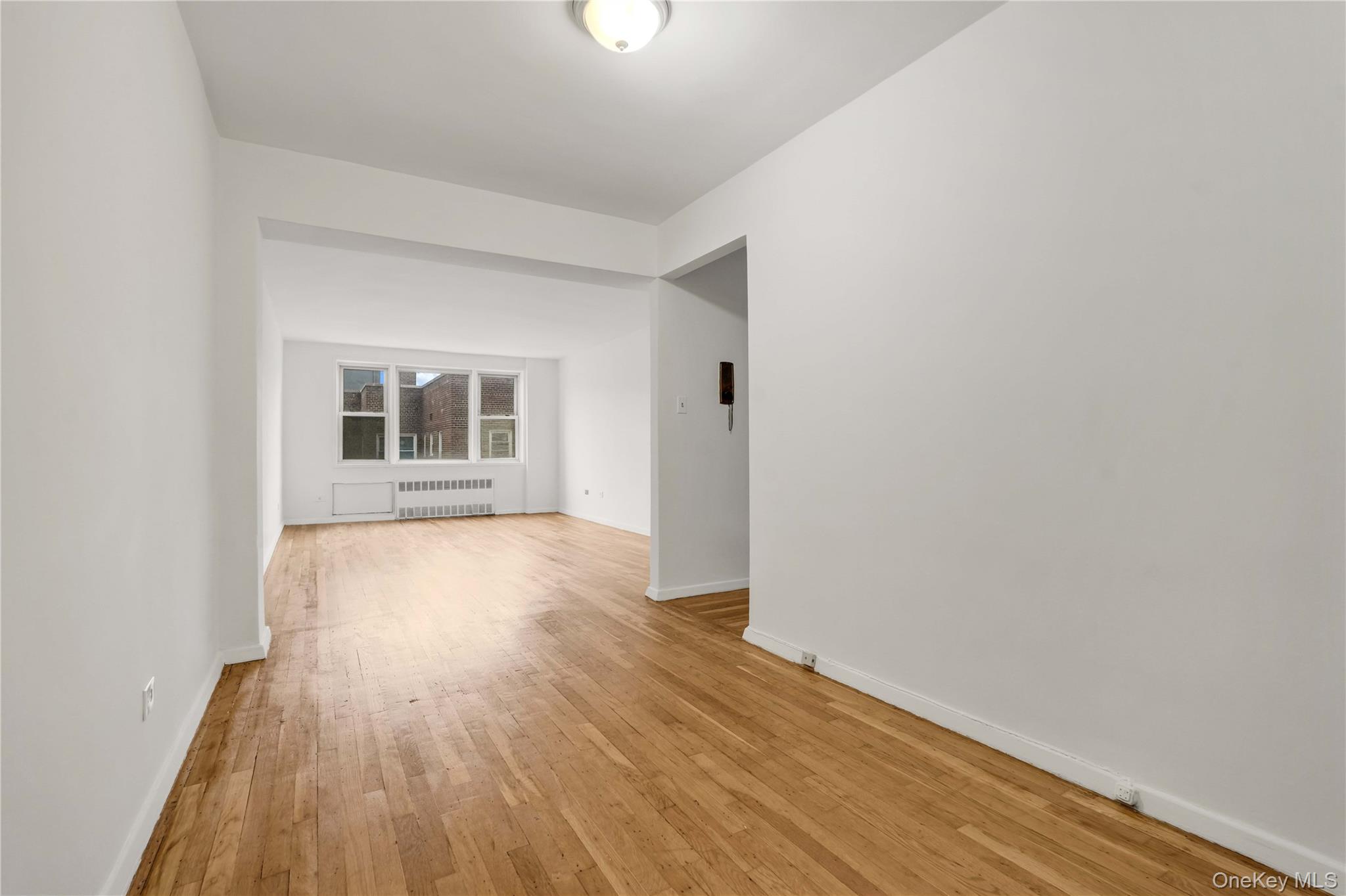110-15 71st Road, Unit 6J Queens, NY 11375 - Photo 6 of 23 an empty room with wooden floor and windows