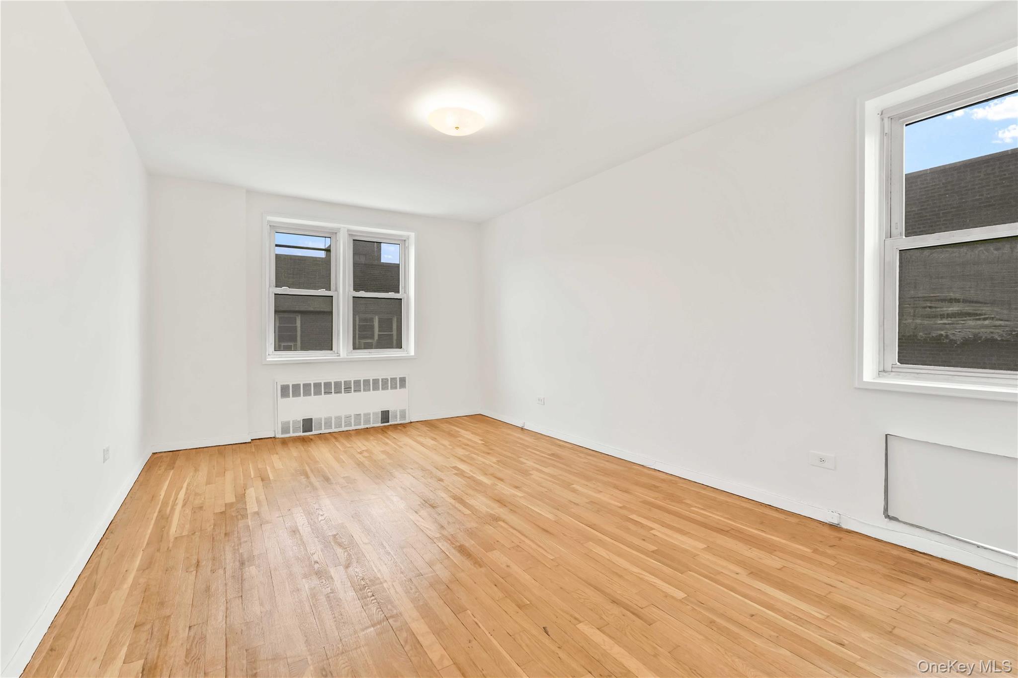 110-15 71st Road, Unit 6J Queens, NY 11375 - Photo 8 of 23 a view of an empty room with wooden floor and windows