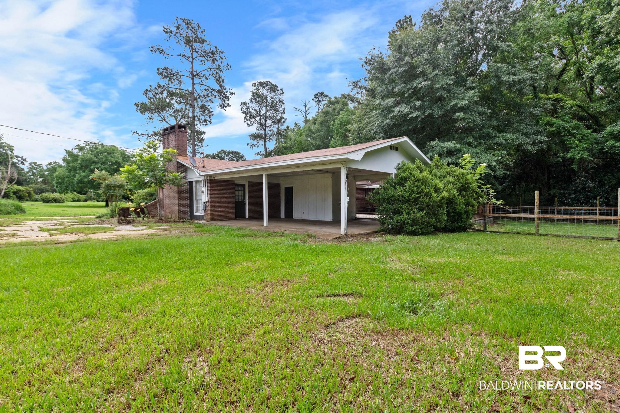 384 Old Bratt Road Atmore, AL 36502 - Photo 52 of 64 Brick exterior with a prominent chimney, covered carport, and a dark entry door