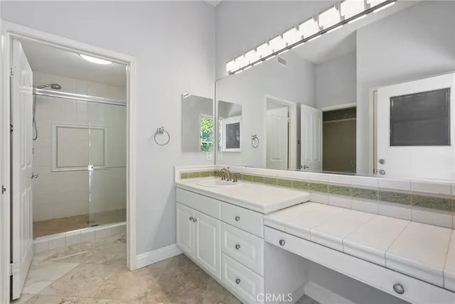 a bathroom with a sink a mirror a vanity and a shower