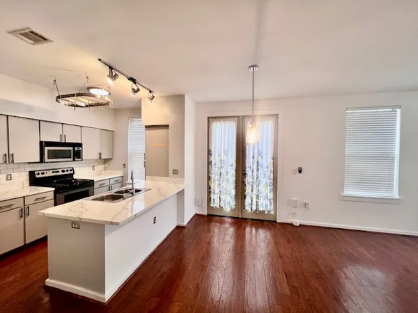 a kitchen with granite countertop a stove top oven a sink dishwasher and a refrigerator with wooden floor