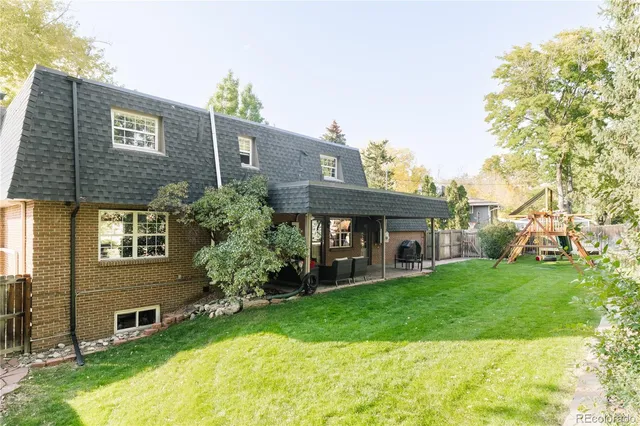 a brick house that has a small yard and large trees