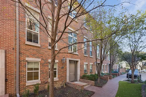 a view of a brick house with a large tree tree front of it
