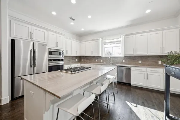 a kitchen with a refrigerator a sink dishwasher a stove and white cabinets with wooden floor
