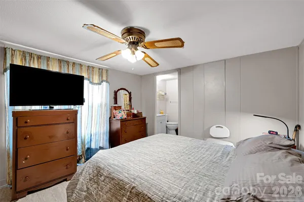 a bedroom with a bed and a flat tv screen on dresser