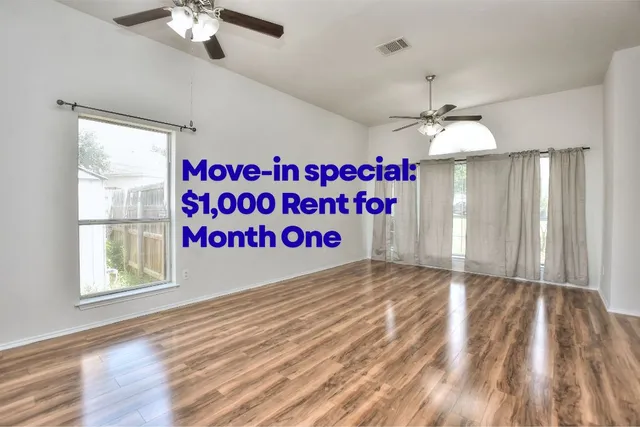 a view of an empty room with a chandelier fan