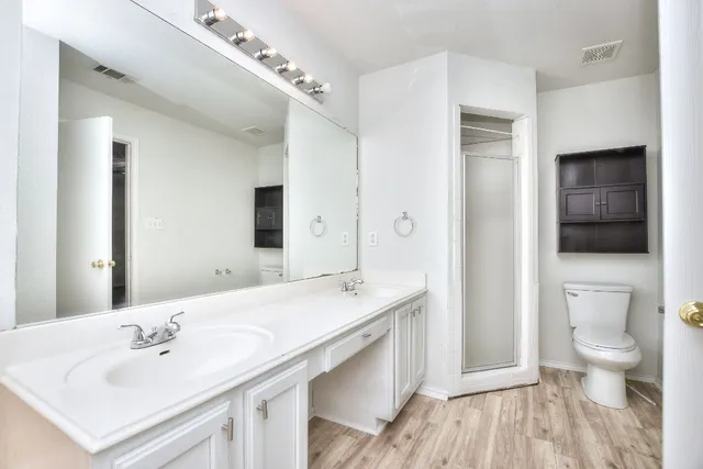 a spacious bathroom with a sink a toilet a shower and a mirror