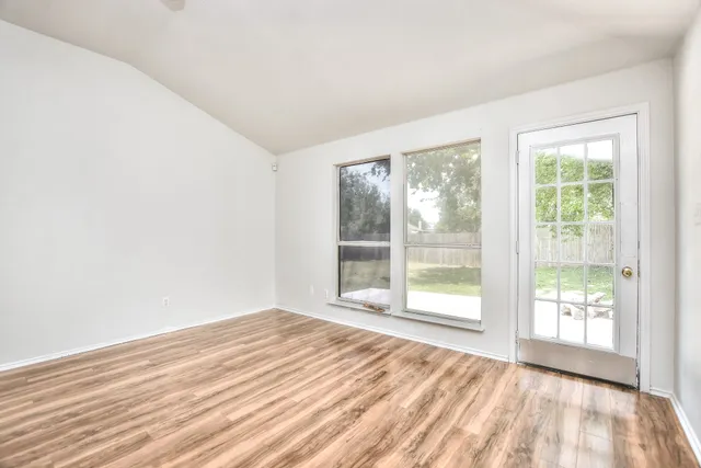 a view of an empty room with wooden floor and a window