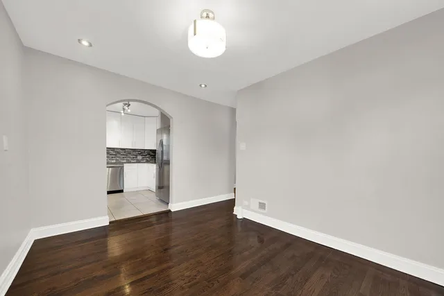 a view of empty room with wooden floor and kitchen