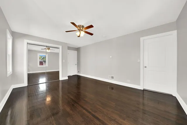 a view of empty room with wooden floor and ceiling fan