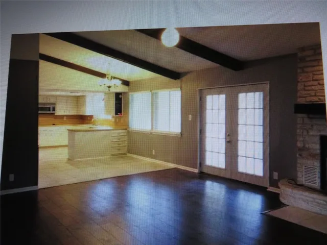 a view of a livingroom with wooden floor and a kitchen