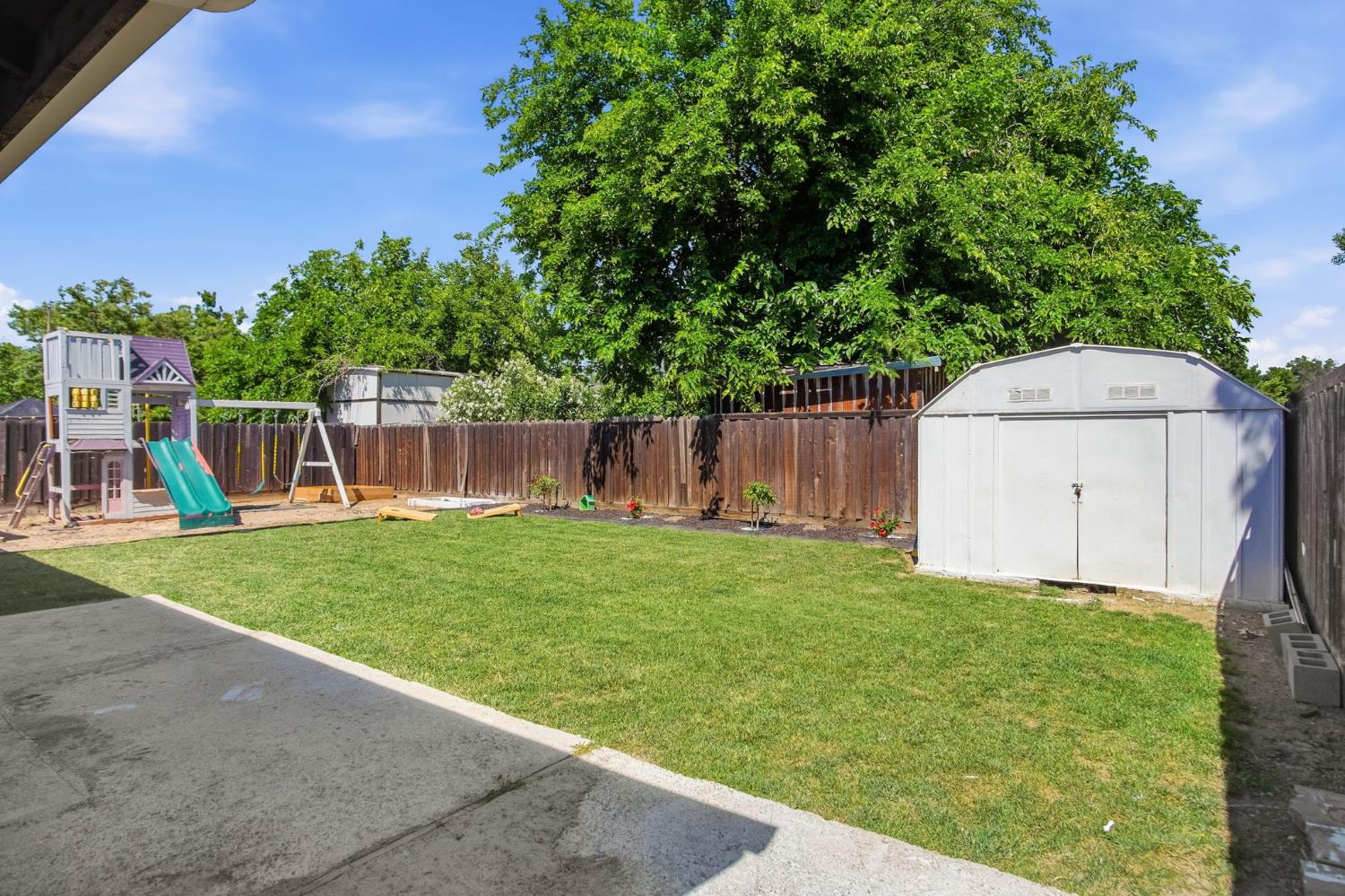1308 Basil Court Newman, CA 95360 - Photo 18 of 20 a view of a backyard with large trees and a wooden fence