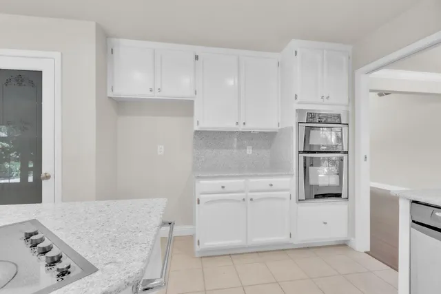 a kitchen with white cabinets and refrigerator