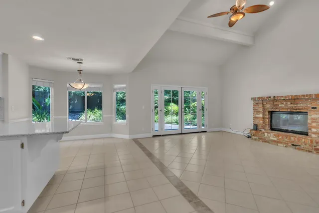 an empty room with windows and fireplace