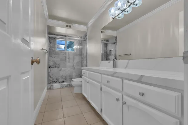 a bathroom with a double vanity sink a toilet a mirror and shower